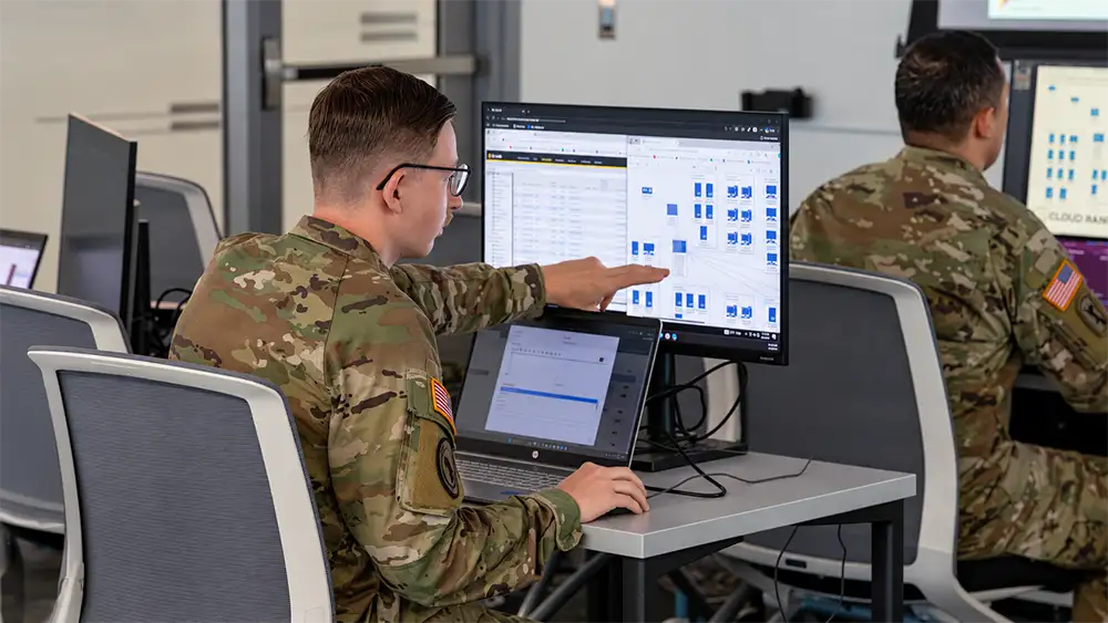 A National Guard soldier points to a network diagram on a computer monitor during a cybersecurity exercise.