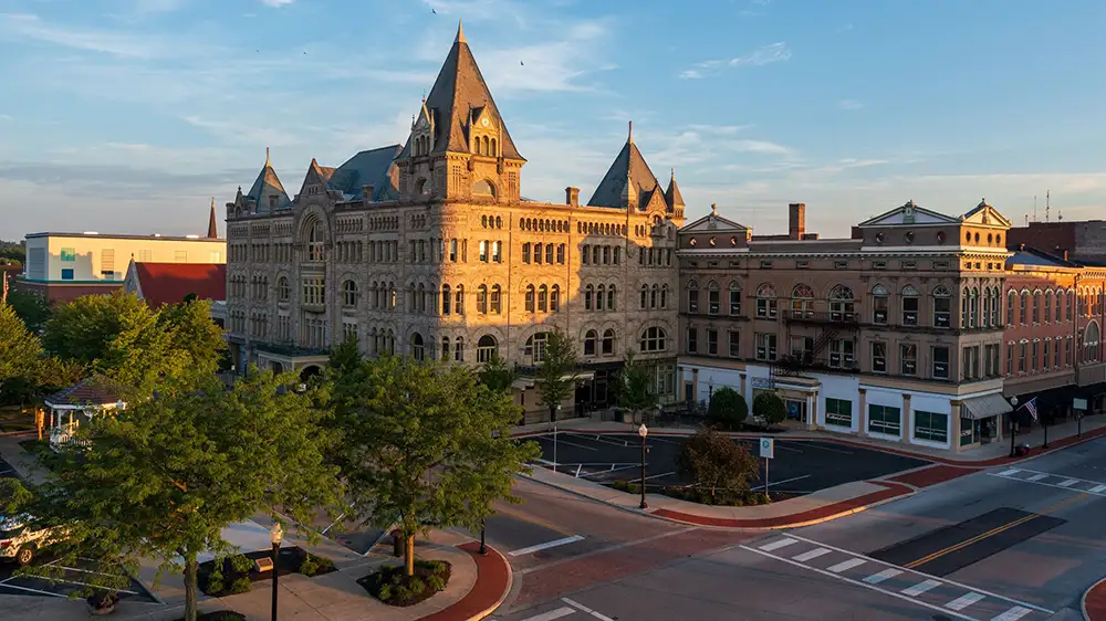 Fort Piqua Plaza, a limestone, castle-like historic building, faces a quiet downtown intersection with neighboring brick storefronts in Piqua, Ohio.