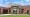 Brick exterior of Cedar County Memorial Hospital with glass entrance doors beneath a curved white canopy on a sunny day.