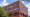 Red-brick office building with rows of arched windows reflecting blue sky and clouds, housing CUSI’s offices in Jonesboro, Arkansas.