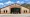 Front exterior of Sangre de Cristo Electric Association's headquarters in Buena Vista, Colorado. The tan-and-peach building features an arched glass entrance, the cooperative's name and logo 